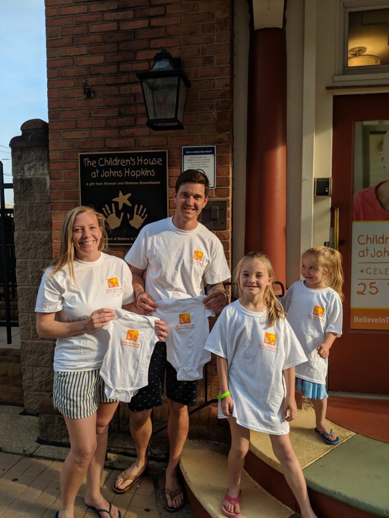 Family smiling in front of the children's house at johns hopkins