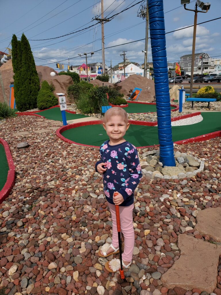 Young girl smiling enjoying putt putt golf while on a Believe In Tomorrow respite trip