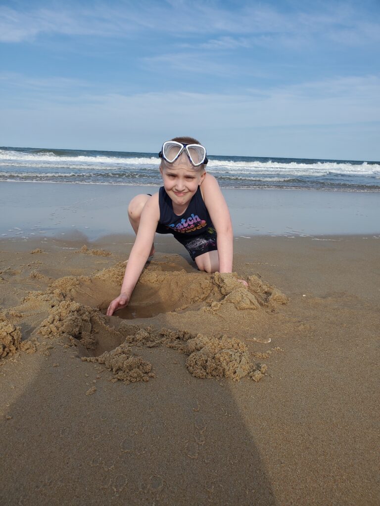 A critically ill child playing in the sand on a respite trip