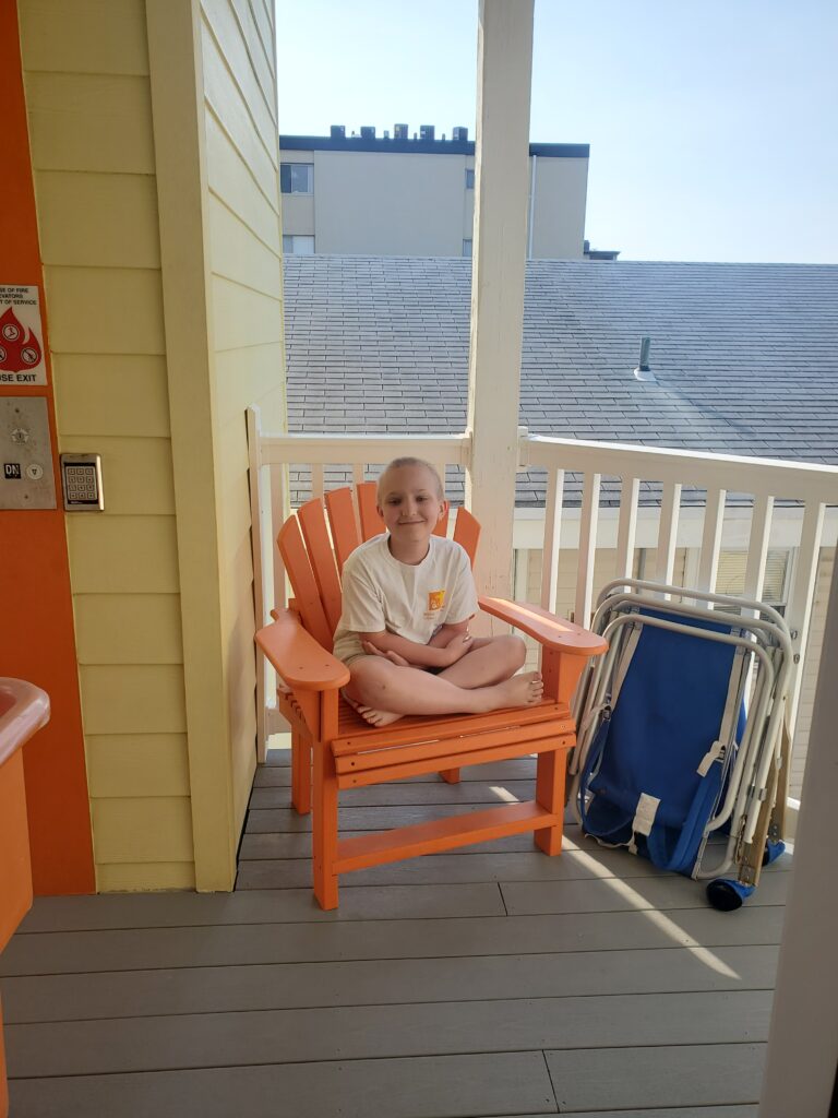 A young bou smiling on the deck of the Children's House by the sea