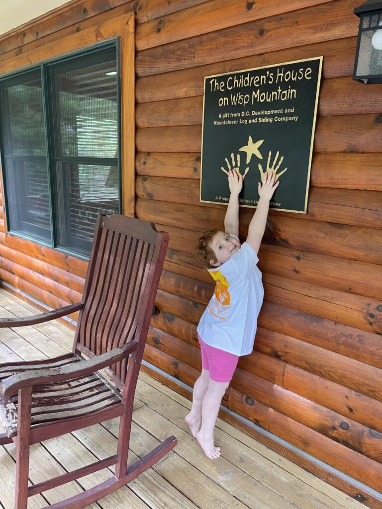 a young girl smiling on the porch of the children's house at wisp mountain